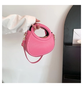 Detail of pink saddle bag featuring vertical texture and a circular cutout handle