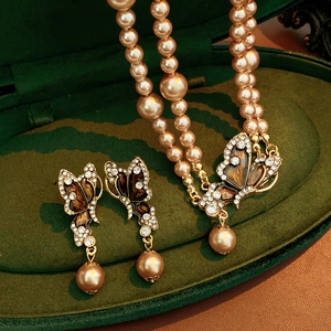 Detailed view of vintage butterfly jewelry set with pearls and enamel in a velvet box