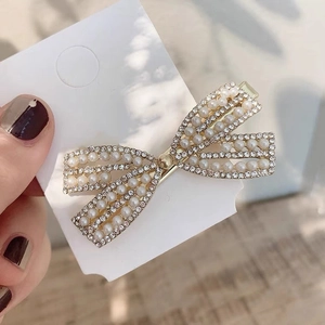 Detail of bow-shaped hair clip with pearls and rhinestones on a gold metal base