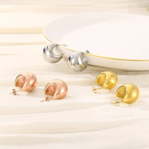Detailed close-up of crescent hoop earrings in gold, silver, and rose gold on silk