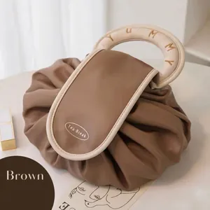 Close-up of brown leather drawstring toiletry bag with round handle and Tea Break logo