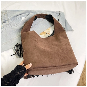 Detail view of the soft brown suede texture and elegant black tassel on the vintage tote bag