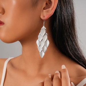 Detail of silver leaf-shaped tassel earrings on model showing metal texture and drape