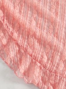 Gros plan sur tissu en maille de dentelle rose avec broderies et bords ondulés