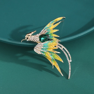 Macro shot of a gold phoenix brooch with green enamel and sparkling rhinestones