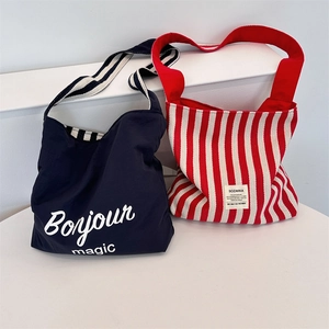 Detail of canvas tote bags featuring navy Bonjour print and red striped texture design