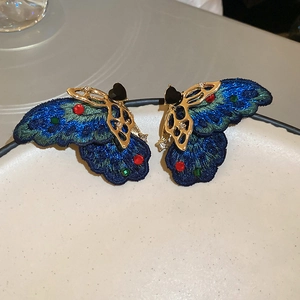 Detailed close-up of embroidered butterfly earrings with crystals and gold metal finish