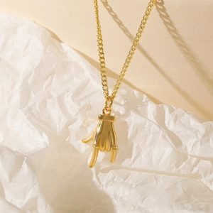 Minimalist gold LOVE hand gesture necklace with zircon inlay on artistic background
