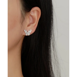 Detailed close-up of a silver butterfly earring with sparkling crystals on a model ear