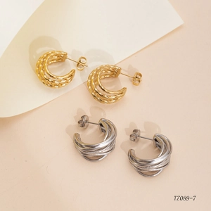 Detailed macro view showing gold and silver twisted C-shape stainless steel earrings