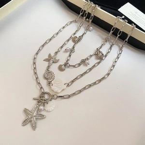 Detail of layered silver starfish shell and pearl necklaces with a toggle clasp closure