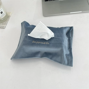 Close-up of blue velvet tissue box cover with gold 'Happiness' embroidery on white desk