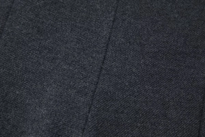 Detailaufnahme der dunkelgrauen Twill-Stoffstruktur und professionellen Nähte des Anzugs