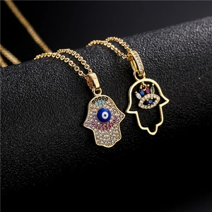 Hamsa Hand pendant necklaces in 18K gold plating with zircon stones on black background
