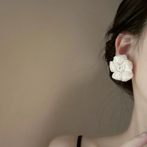 Close-up of elegant flower earring with pearl center and metallic wire details