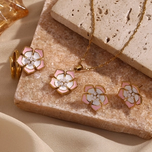 Detail of floral jewelry set with pink white enamel petals and pearl center in gold