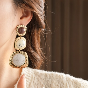 Close-up of vintage geometric earrings with brown resin and grey marble pendants