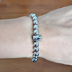 Detailed close-up of a silver beaded bracelet with a crown pendant worn on a wrist