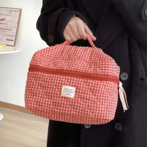 Dettaglio della borsa cosmetica trapuntata a quadretti rossi con manico superiore