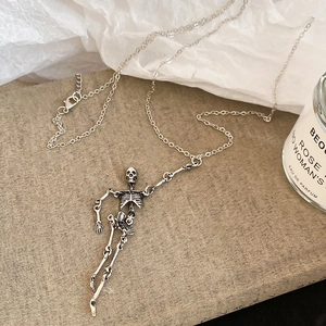 Silver skull necklace set in gothic style displayed on books with soft natural lighting