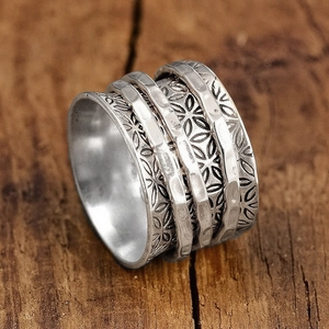 Close-up of vintage silver spinner ring with floral textures and hammered finish detail