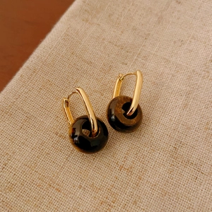 Elegant gold U-hoop earrings featuring vintage Tiger's Eye stone beads on a linen background