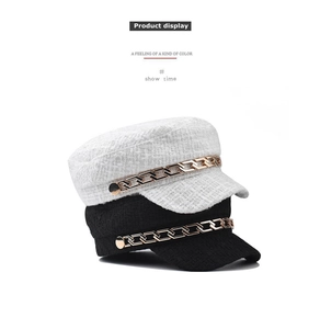 Detail of tweed newsboy cap with bold golden metal chain and textured woven fabric