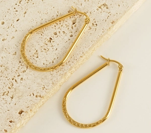 Détail de boucles d'oreilles goutte dorées 18K avec motifs en relief et fermoir sûr