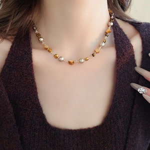 Nahaufnahme der Retro-Perlenkette mit Tigerauge-Steinen und Perlen am Hals des Models