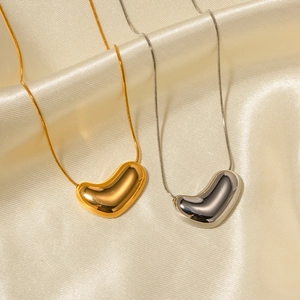 Dettaglio di ciondoli a cuore lucidati in oro e argento su catene a serpente fini