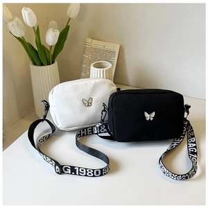Detail view of nylon crossbody bags with butterfly metal logo and wide lettered straps