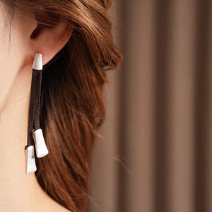 Close-up of model wearing silver irregular earrings with dark brown leather fringe
