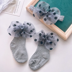 Detail of grey infant socks with anti-slip lettering and matching polka dot bow headband