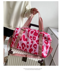Pink cow print travel tote placed on a suitcase featuring wet dry separation