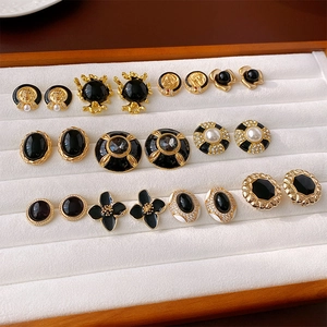 Flat lay of vintage gold-tone stud earrings with black stones and pearls on white velvet
