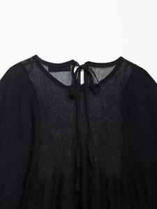 Detail view of the black semi-transparent knit top with elegant lace-up back design