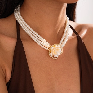 Detail showing multi-layer faux pearl necklace with diamond-set flower pendant