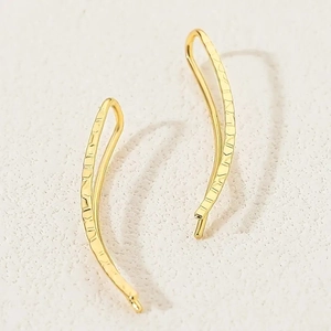 Detailed macro view of gold-colored geometric earrings with hammered finish and texture