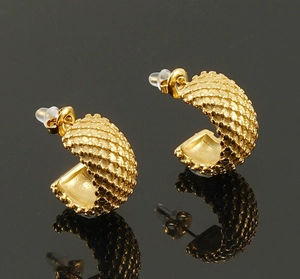 Detailed view of C-shaped golden earrings with textured dot patterns and silicone backs