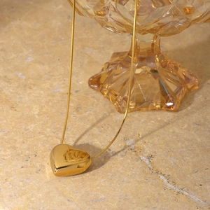 Minimalist gold heart necklace with sleek snake chain on a marble background