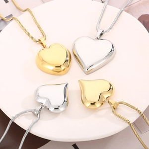 Detailed flat lay of long titanium steel necklaces with hollow heart pendants in gold and silver