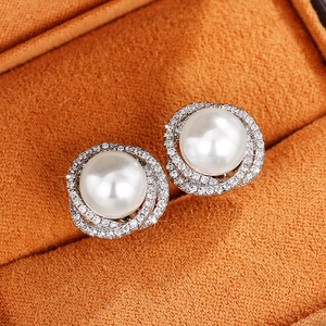 Macro shot of pearl earrings with micro-inlaid zircon halo on orange velvet