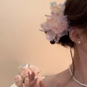 Dettaglio di un fermaglio per capelli a fiore in rete con nappe di perle e rosa sfumato