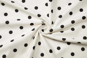 Close-up of white fabric with black polka dots showing soft texture and fluid drape