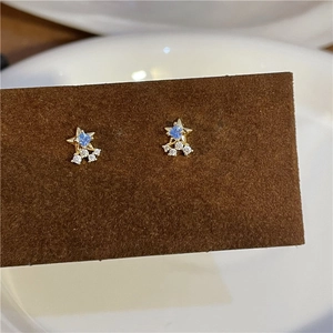 Detailed close-up of golden star earrings with blue zircon and white crystal accents