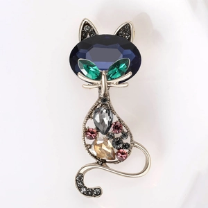 Close-up of vintage cat brooch with blue gemstone and colorful crystals on silver base