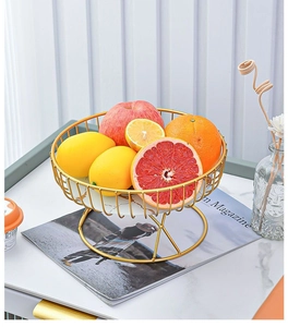 Détail d'un panier à fruits en fil doré avec base en marbre et assortiment de fruits