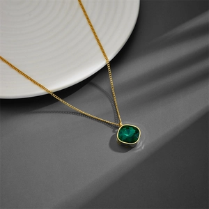 Gold titanium steel necklace featuring a green square zircon pendant on a ceramic dish