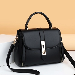 Retro black leather handbag with gold buckle and adjustable strap on a studio background