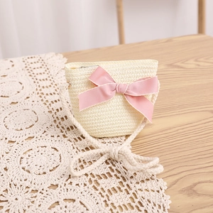 Détail du sac bandoulière en paille pour enfants avec nœud rose sur bois et dentelle